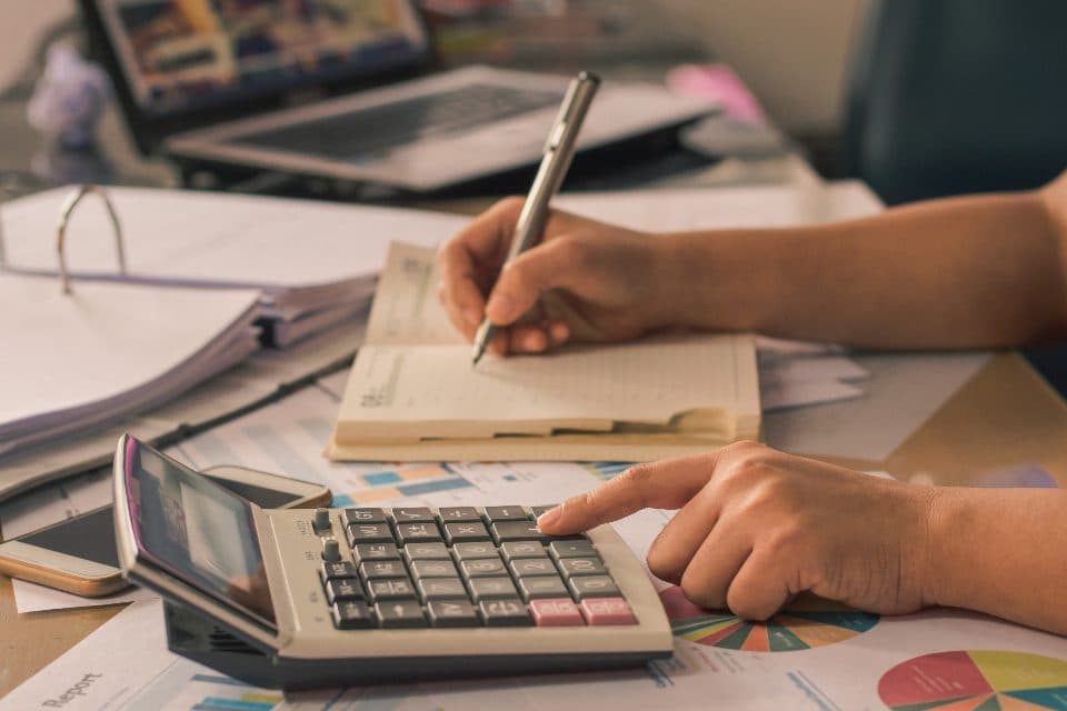 Mãos fazendo cálculos com calculadora e documentos contábeis