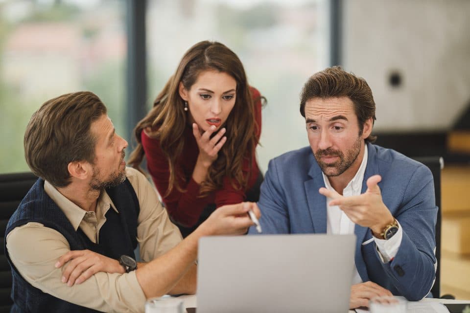 Equipe analisando dados em um notebook durante reunião de trabalho
